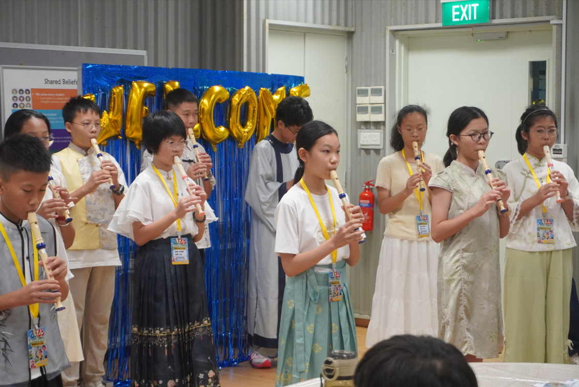 A group of students in traditional attire standing in a row and playing recorders together.